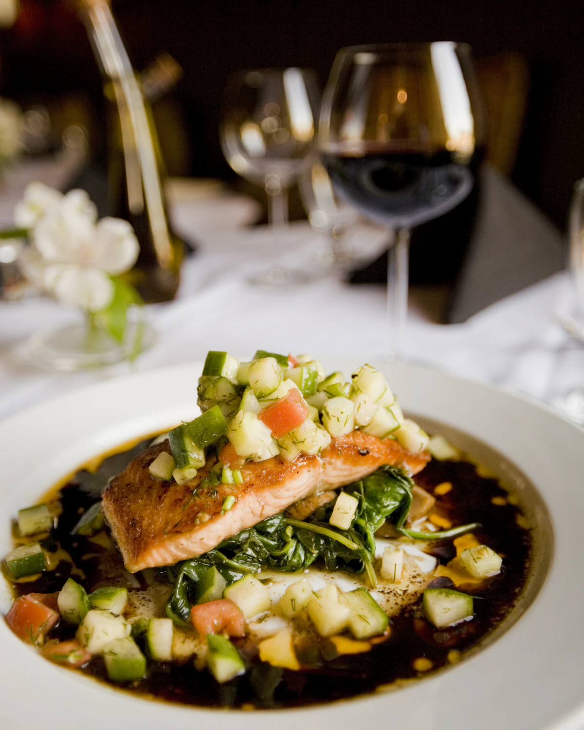Seared seasonal fish fillet with citrus and fresh herbs plated on a green backdrop