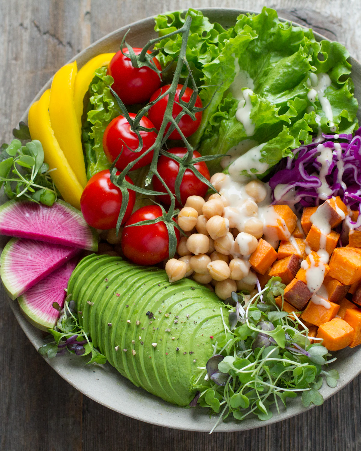 Overhead view of Foglia & Co.'s signature grain bowl with roasted vegetables, herbs and citrus on a purple backdrop