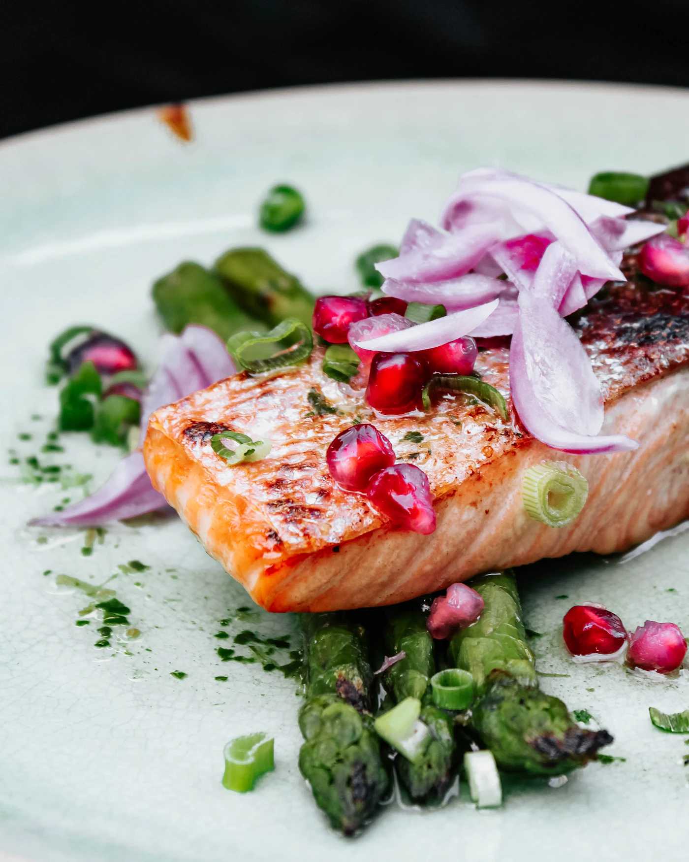Citrus-seared salmon fillet with orange segments and fresh herbs on an orange background