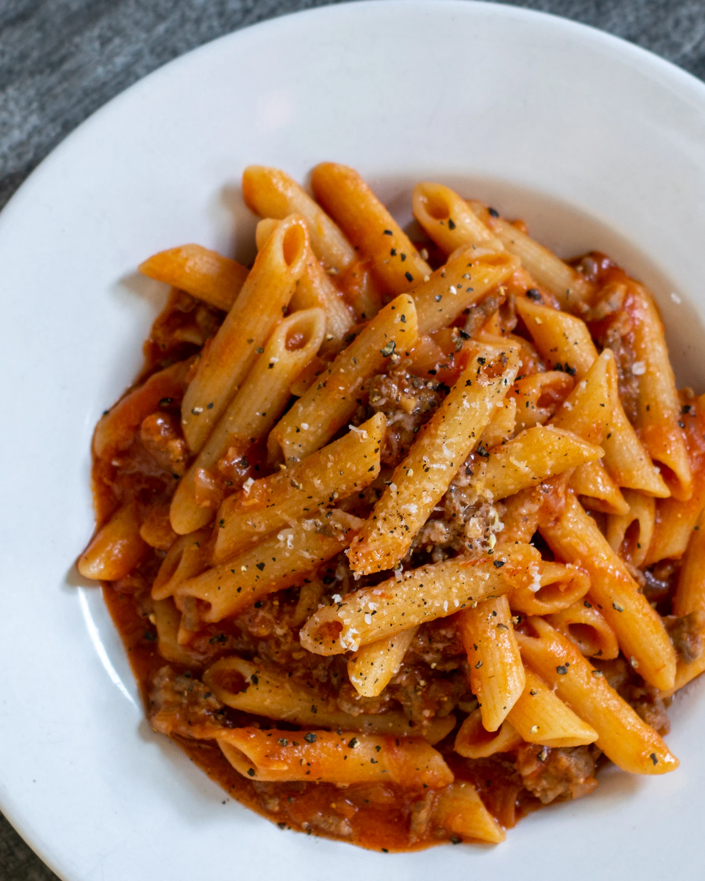 Spiced pasta nest with tomato sauce pockets, chili flecks and basil on an orange background